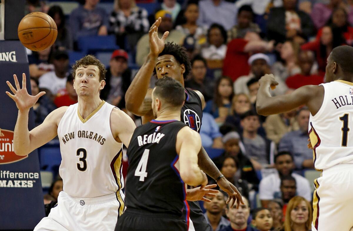 Pelicans center Omer Asik (3) receives a pass from guard Jrue Holiday past Clippers guard J.J. Redick (4) and center DeAndre Jordan in the first half.