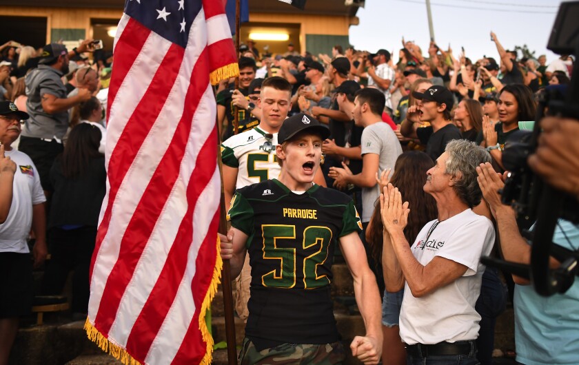 Fans cheer as graduated players from last year’s Paradise football team enter the stadium before Friday’s season opener.
