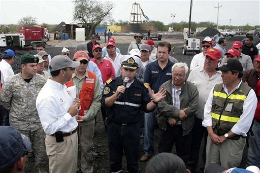 Chile's Navy Cmdr. Renato Navarro, center, accompanied by Mexico's Labor Secretary Javier Lozano Alarcon, center left, speaks to relatives of trapped miners at a coal mine in San Juan de Sabinas, Coahuila state, Mexico, Wednesday, May 4, 2011. Labor Secretary Javier Zolano announced the recovery of the seventh body at the coal mine in a Twitter message Friday. Seven other miners remain missing at the mine in the town of San Juan Sabinas, where an explosion Tuesday also injured a teenage miner, who lost an arm. (AP Photo/Alberto Puente)
