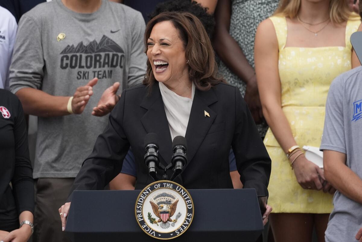 Vice President Kamala Harris smiles while speaking from behind a lectern.