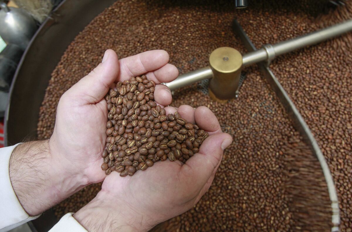 Head roaster Nick Berardi makes a heart with roasted Guatemalan coffee beans at the Mostra warehouse in Carmel Mountain area.