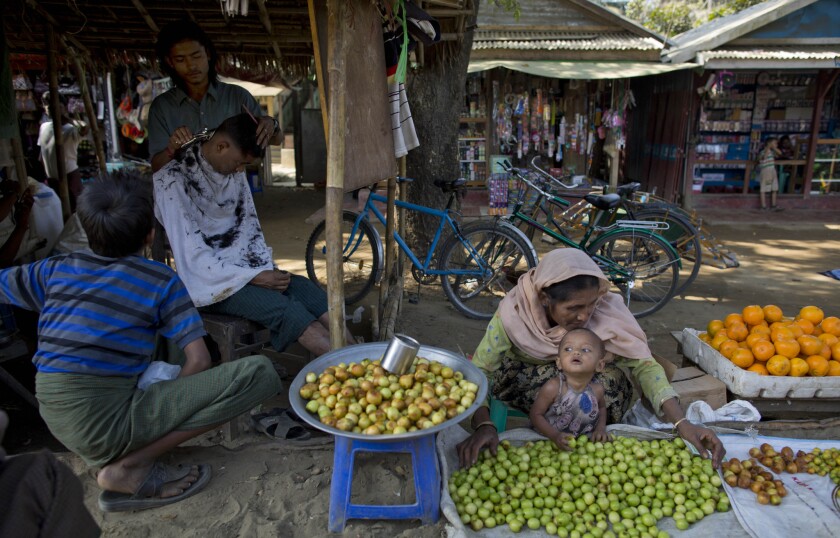 A Muslim barber gives a customer a haircut at an open-air barber shop and market in Rakhine state, Myanmar.