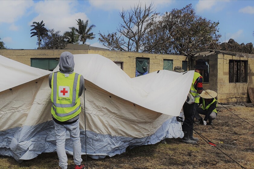 En esta foto proporcionada por la Sociedad de Cruz Roja de Tonga, personal de Cruz Roja instala un refugio temporal en Sopu, Nukualofa, el sábado 22 de enero de 2022, mientras la nación insular de Tonga lidiaba con los efectos de una erupción volcánica submarina y un tsunami. (Sociedad de Cruz Roja de Tonga via AP)