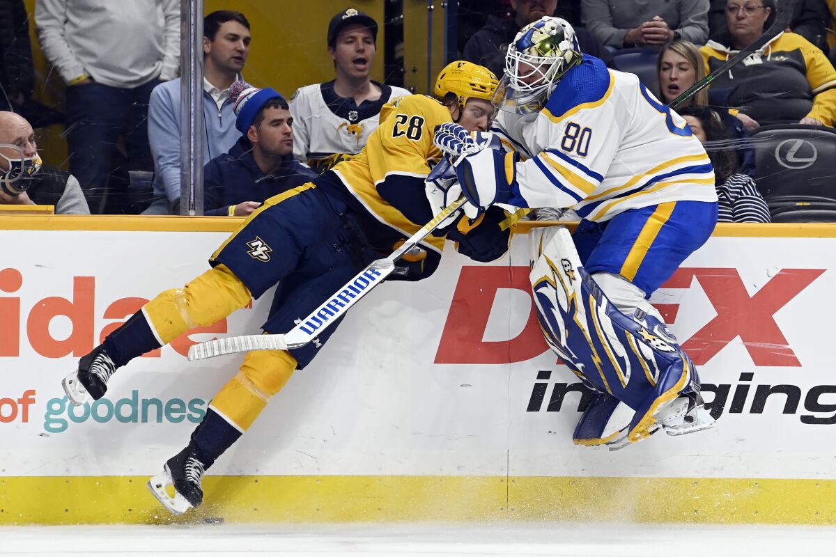 Nashville Predators right wing Eeli Tolvanen (28) collides with Buffalo Sabres goaltender Aaron Dell (80) during the second period of an NHL hockey game Thursday, Jan. 13, 2022, in Nashville, Tenn. Dell was attempting to clear puck away from Predators defenders. (AP Photo/Mark Zaleski)