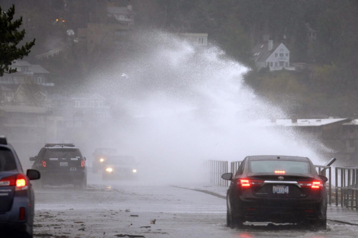 Un ventarrón impulsa una ola desde la orilla, en medio de una tormenta invernal, en una carretera en Seattle.