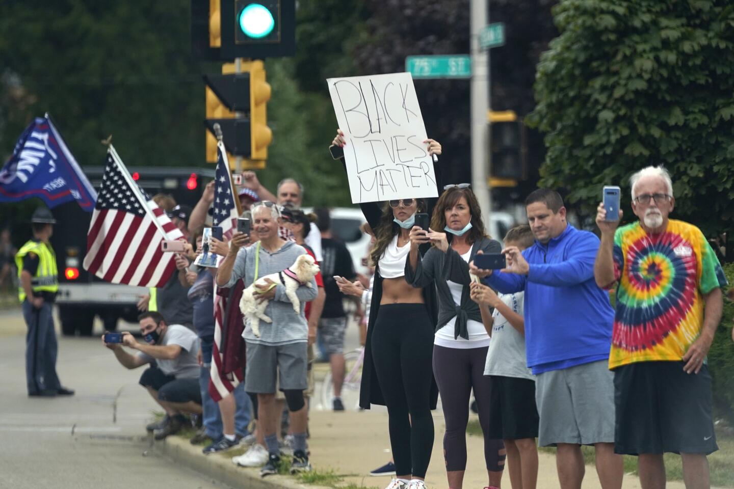 People line up to watch as the motorcade with President Donald Trump passes by.