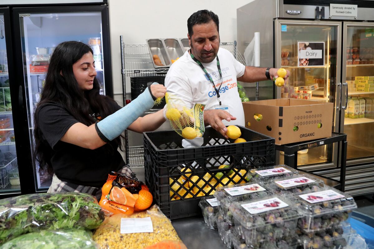 Volunteers Email Ahmadzai and Isabella Filorio help restock fresh produce at South County Outreach.