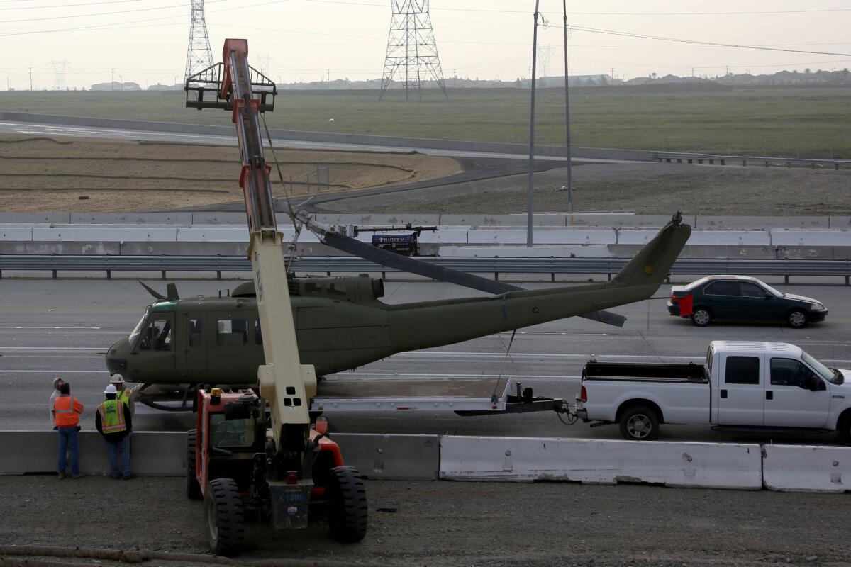 A prop helicopter is put back on its carrier after hitting the side of an overpass and toppling onto the highway.