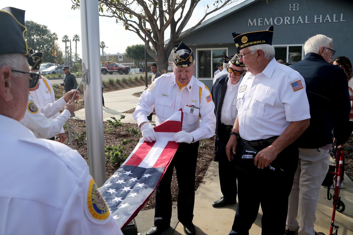 American Legion Post 133 color guard Dennis Bauer, center, folds an American flag after the dedication ceremony on Saturday.