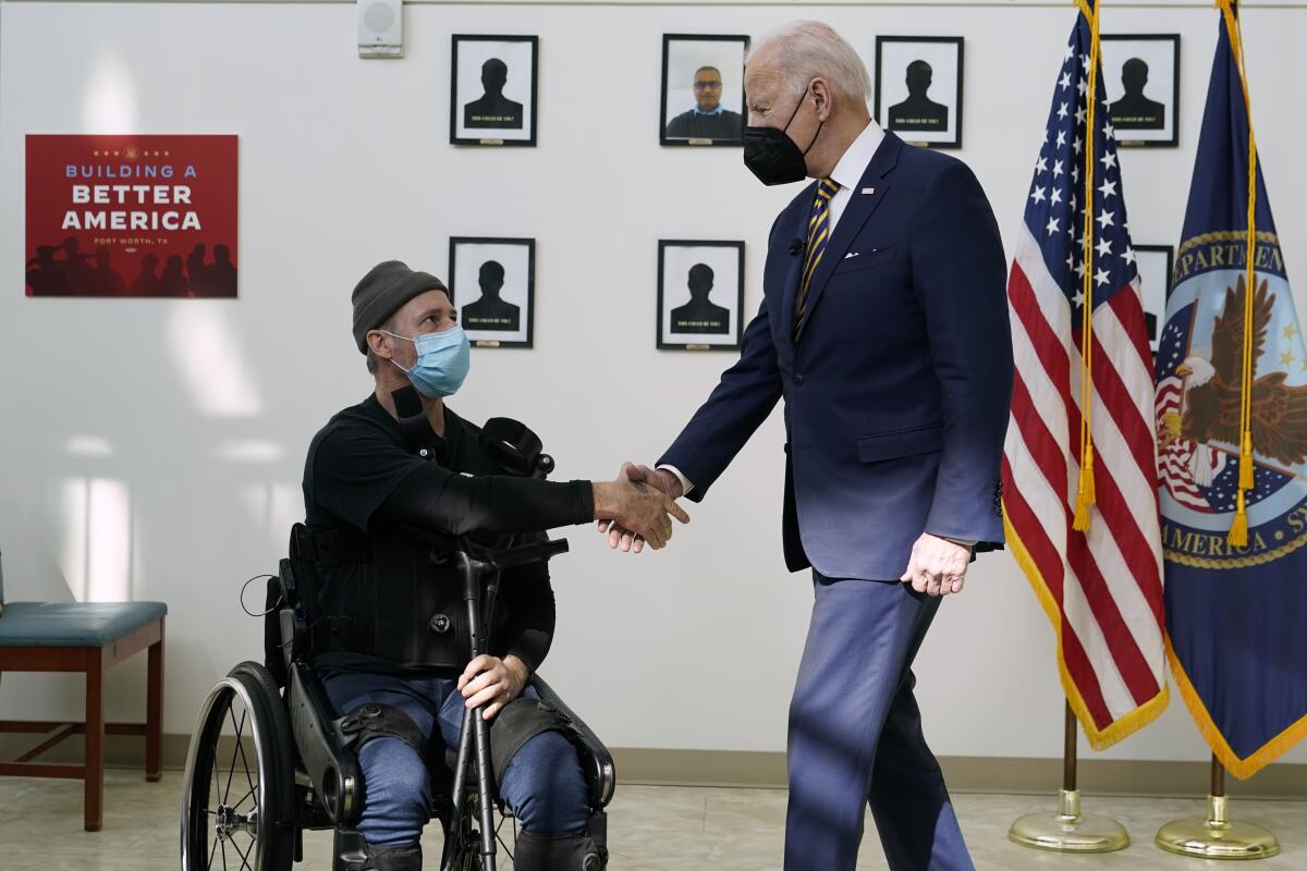 President Biden shakes hands a veteran in a wheelchair.