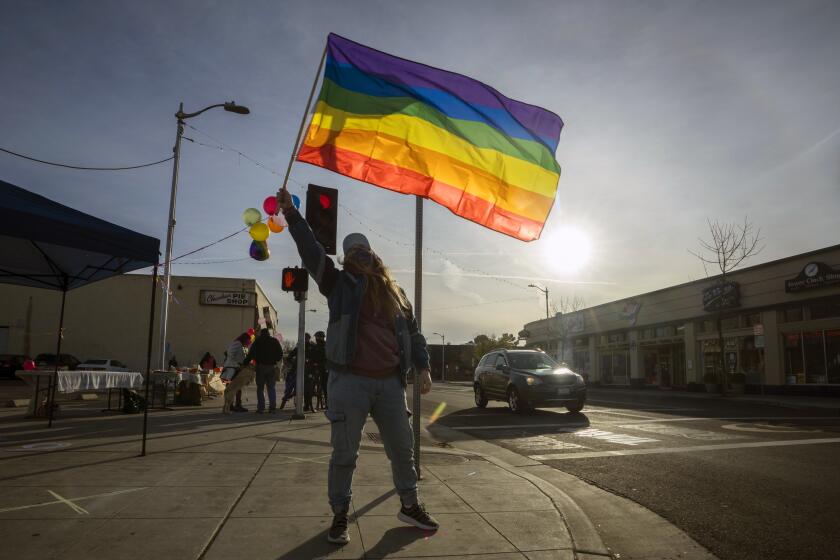 FRESNO, CA FEBRUARY 14, 2021 - Nicole Spate waves a gay pride flag at a gathering of gay and straight community members to protest the recent purchase of the Tower Theater by an evangelical church. Many are concerned in the community that there will be anti-gay sentiment and activity in the small arts community. (Tomas Ovalle / For The Times)