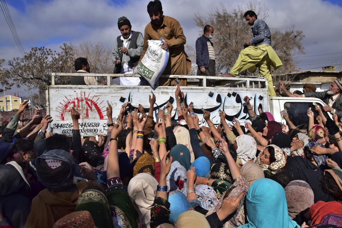 ARCHIVO - Gente forcejea para comprar talegos de harina de trigo subsidiada en Quetta, Pakistán, 