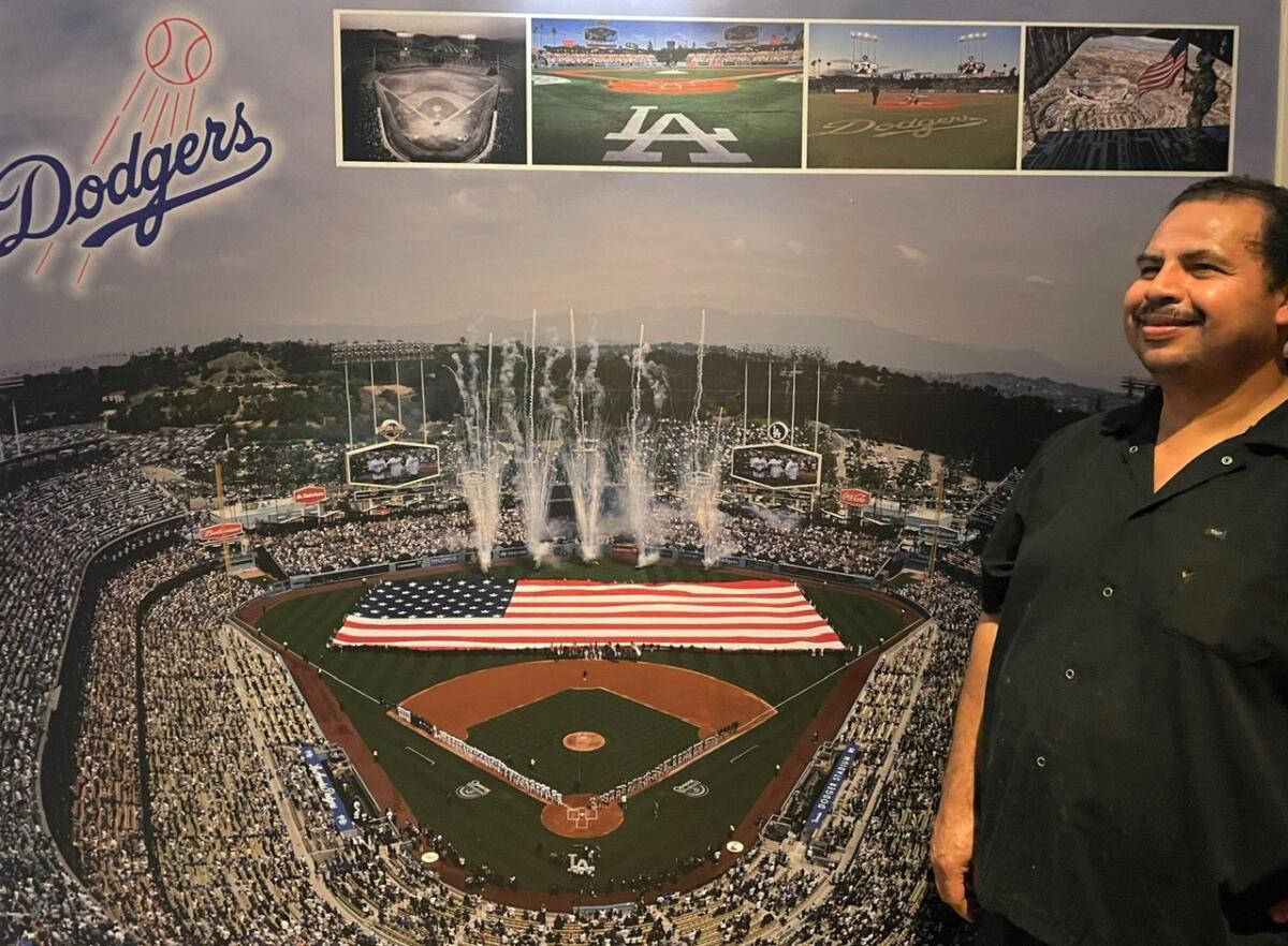 Juan Gomez stands in front of a large photo of Dodger Stadium at his restaurant Penne Pasta in Lahaina, Hawaii.