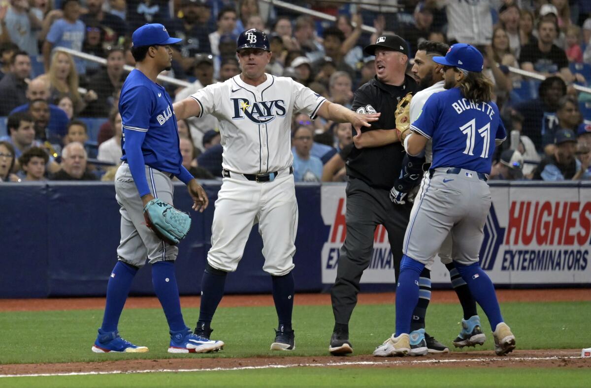 Tampa Bay Rays third base coach Brady Williams, center left, umpire Corey Blaser and Toronto Blue Jays shortstop Bo Bichette (11) try to break up a confrontation between Tampa Bay's Jose Caballero, second right, and Toronto Blue Jays reliever Genesis Cabrera, left, during the seventh inning of a baseball game, Saturday, March 30, 2024, in St. Petersburg, Fla. (AP Photo/Steve Nesius)
