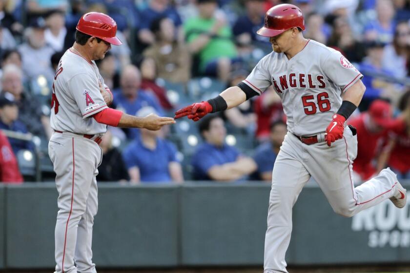 Los Angeles Angels' Kole Calhoun is congratulated by third base coach Mike Gallego after hitting a go-ahead two-run home off Seattle Mariners' Roenis Elias during the eighth inning of a baseball game Saturday, June 1, 2019, in Seattle. The Angels won 6-3. (AP Photo/John Froschauer)