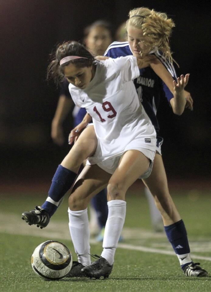 Estancia High's Haley Flores (19) keeps the ball out of Newport Harbor's Peyton Groves reach as they compete during the second half in a nonleague game at Jim Scott Stadium on Thursday.