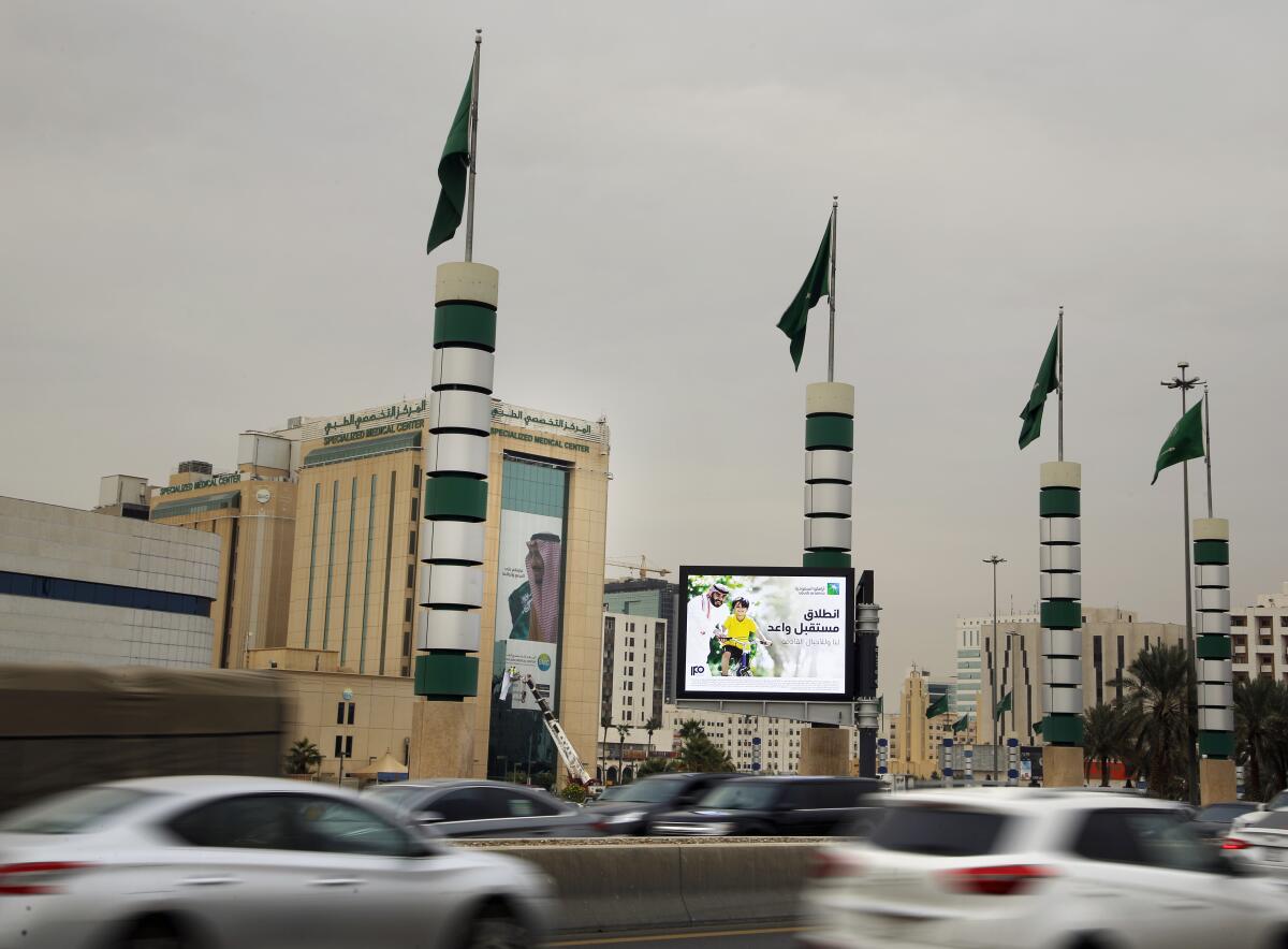 Vehicles pass in front of an illuminated advertisement for Saudi Aramco in Riyadh, Saudi Arabia.