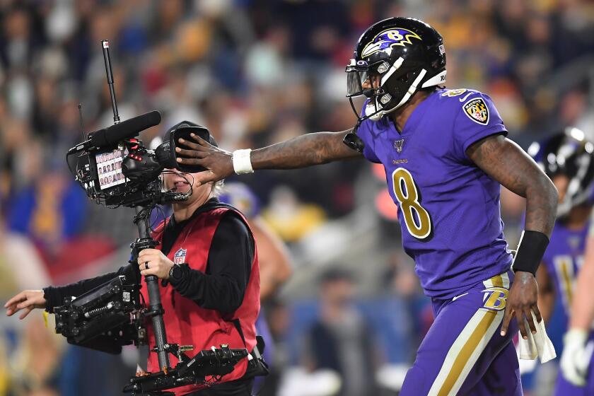 LOS ANGELES, CALIFORNIA NOVEMBER 25, 2019-Ravens quarterback Lamar Jackson covers the lens form a televison cameraman after his team scored a touchdown against the Rams in the 4th quarter at the Coliseum Sunday. (Wally Skalij/Los Angerles Times)