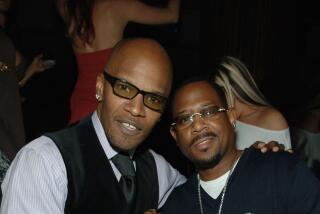 Jamie Foxx and Martin Lawrence clasp hands and look straight ahead