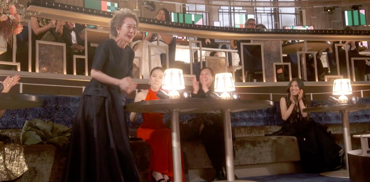 Yuh-jung Youn, wearing a black dress, stands up to accept her award for supporting actress. 