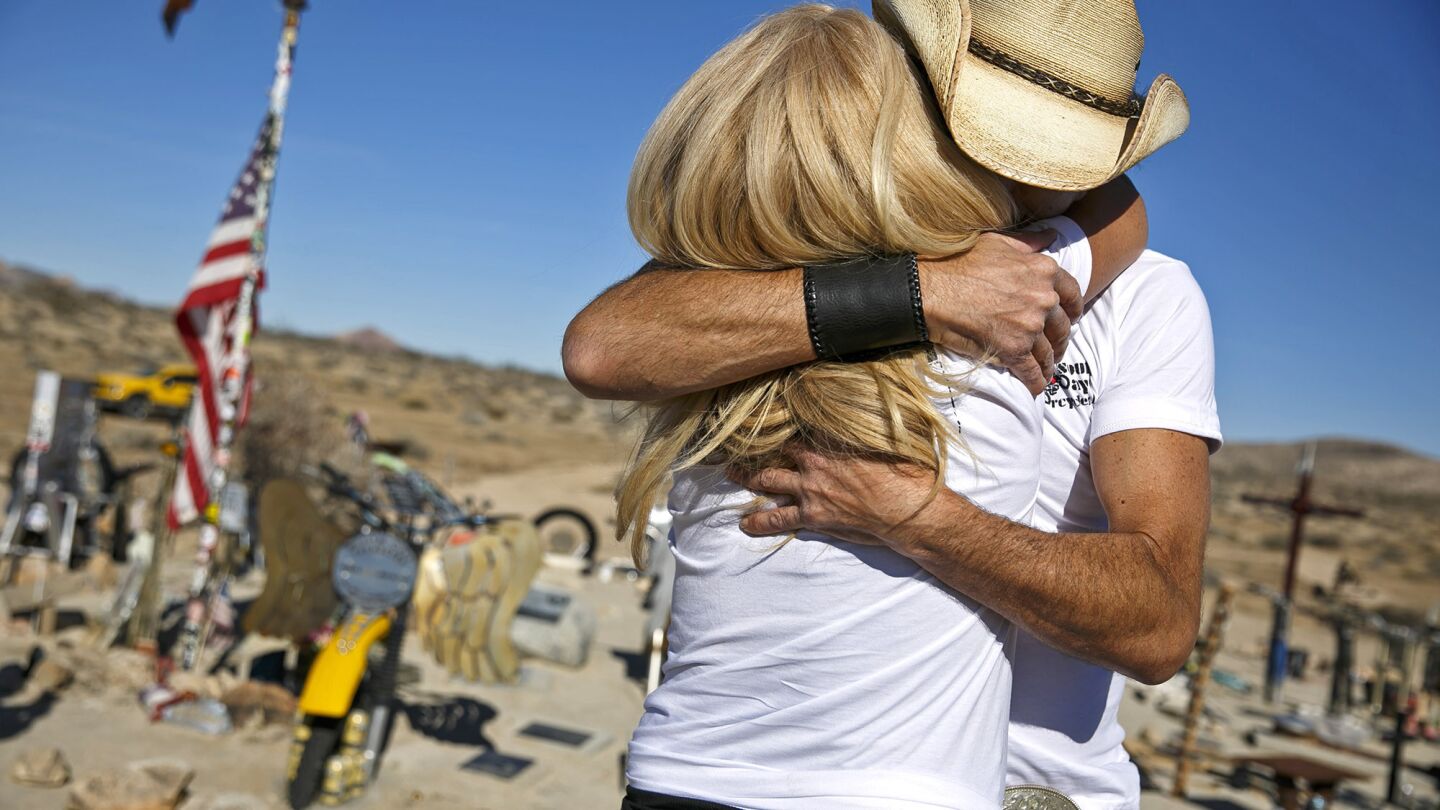 Pat Verfuerth, left, and Billy Tuchscher embrace after unveiling a motorcycle memorial for the late William Cory Tuchscher at the Husky Monument near Randsburg, Calif.