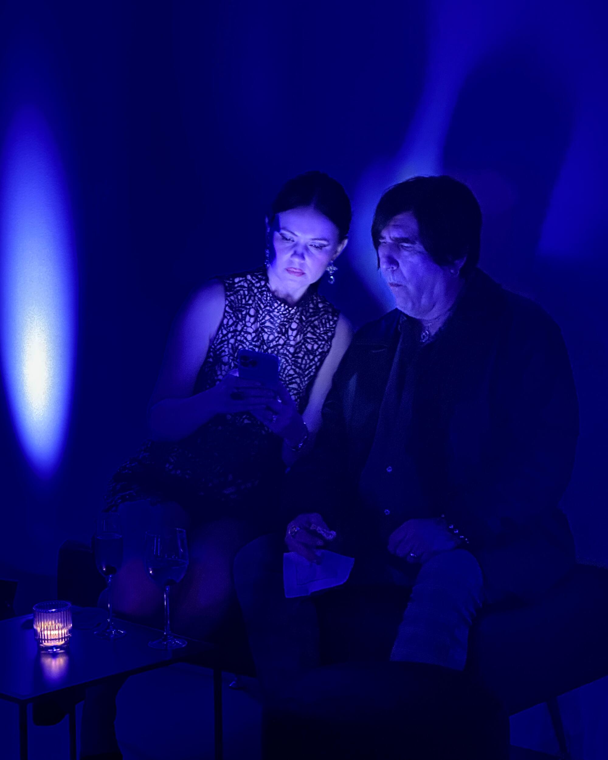 Two women looking at their phones bathed in blue light.