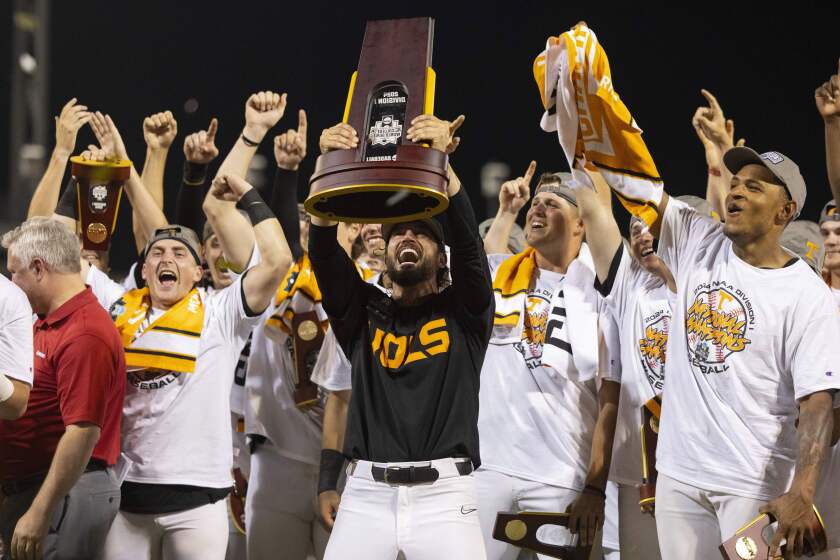 Tennessee coach Tony Vitello, center, hoists the championship trophy.