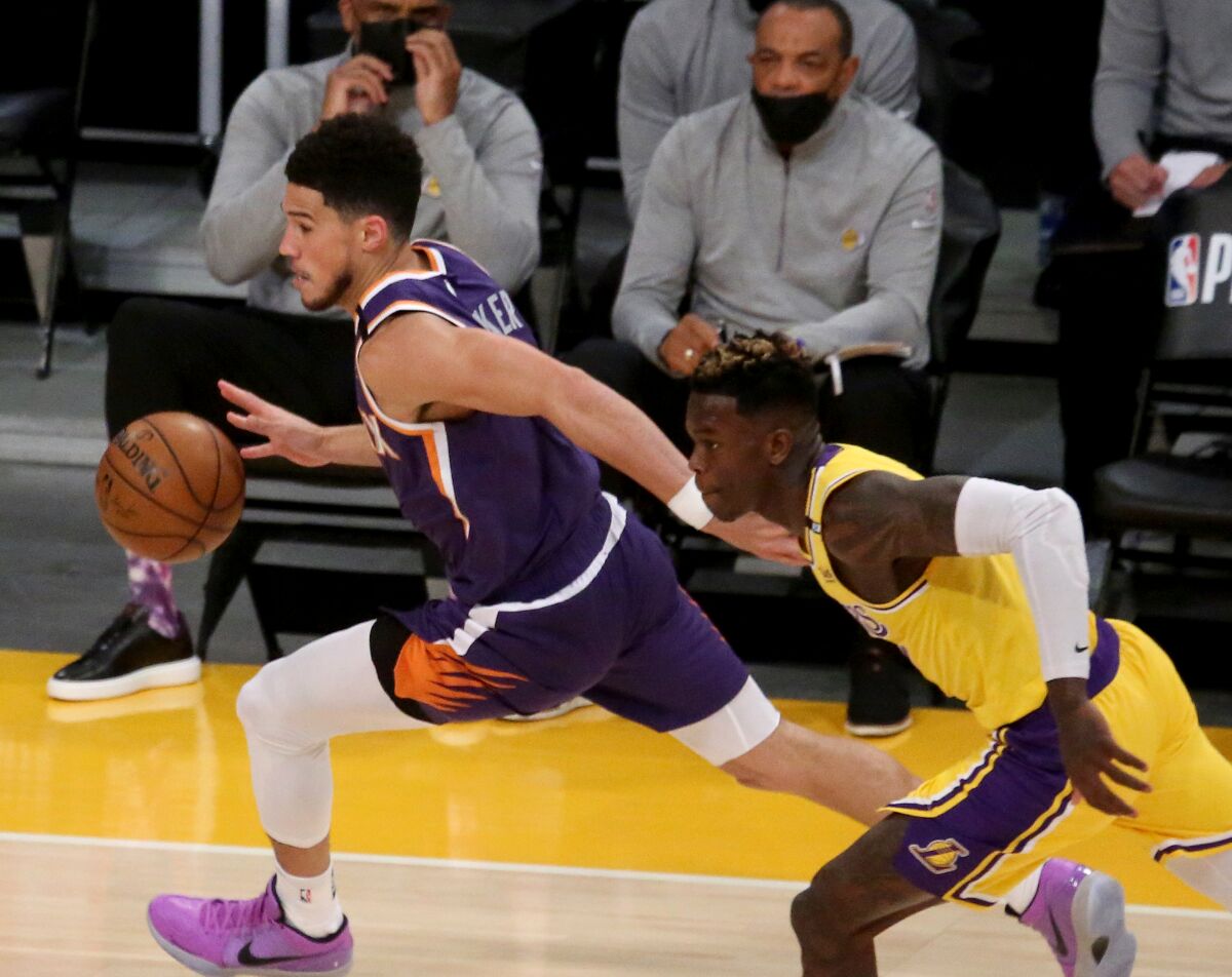 Suns guard Devin Booker drives with the ball ahead of Lakers guard Dennis Schroder.