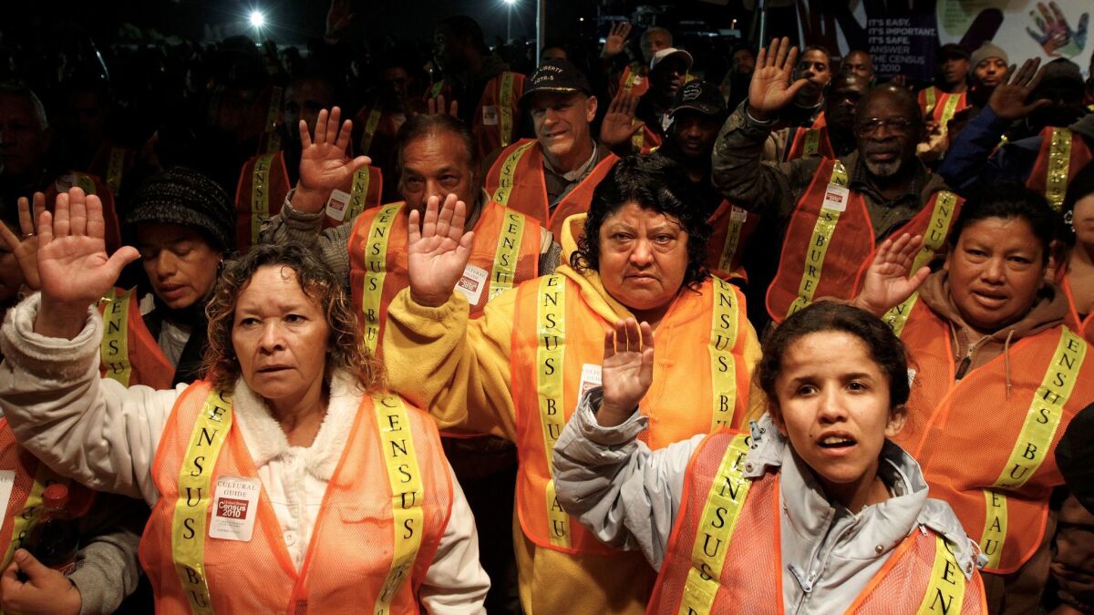 Census Bureau enumerators in orange vests raise their right hands to take an oath.