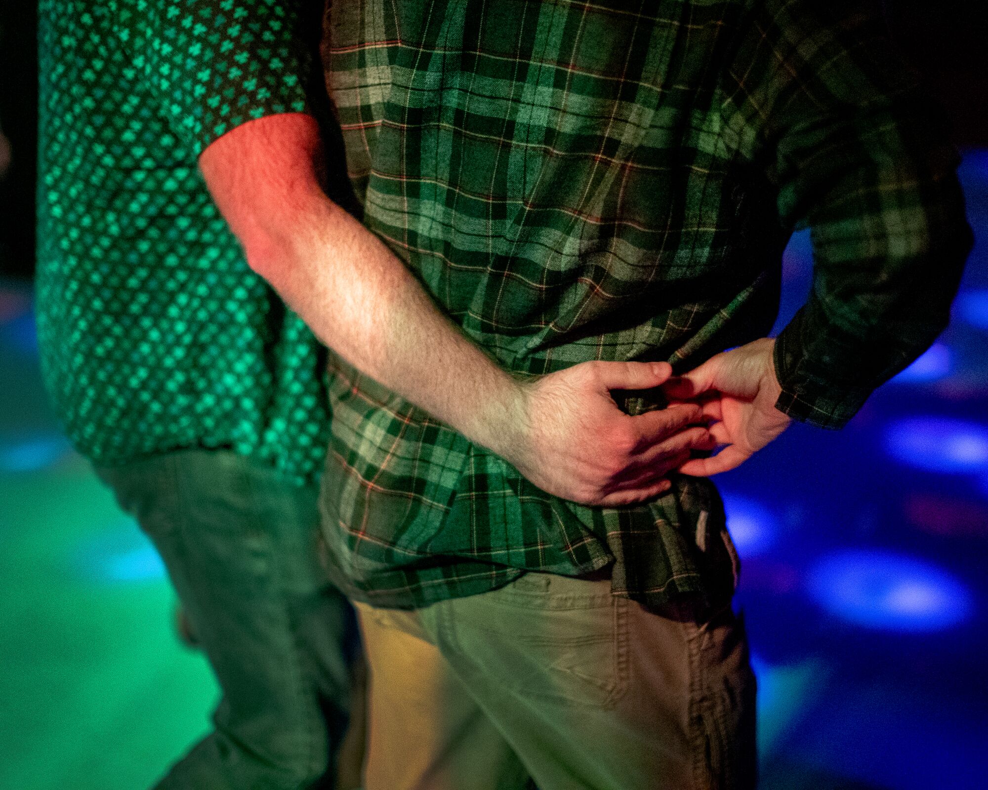 Two people, one in a polo and one in flannel, hold each other as they dance by.
