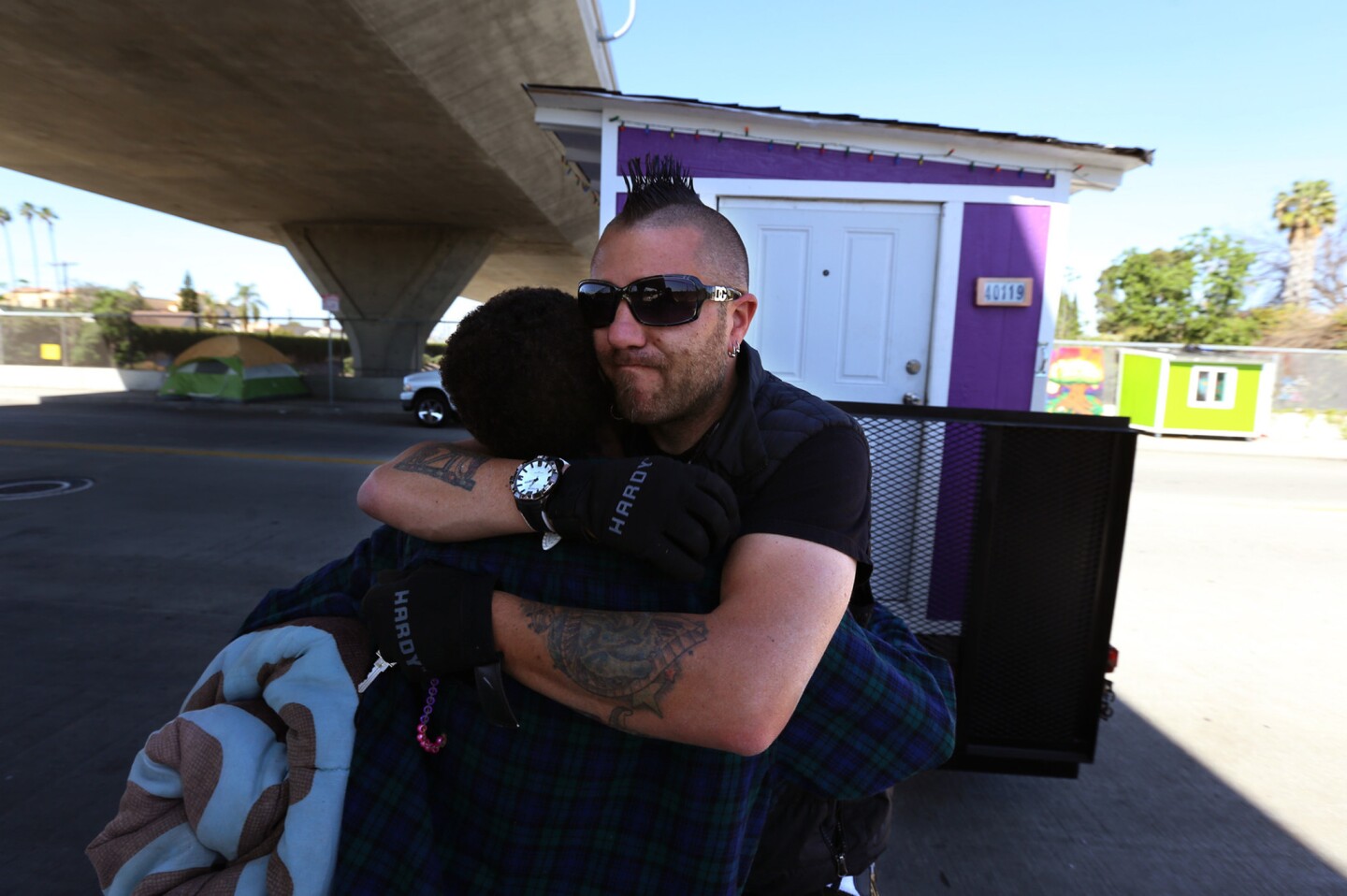 Julia Briggs Cannon, 58, left, receives a hug from Elvis Summers, who built the tiny houses and donated them. He's moving Cannon's house to storage before the city can impound it.