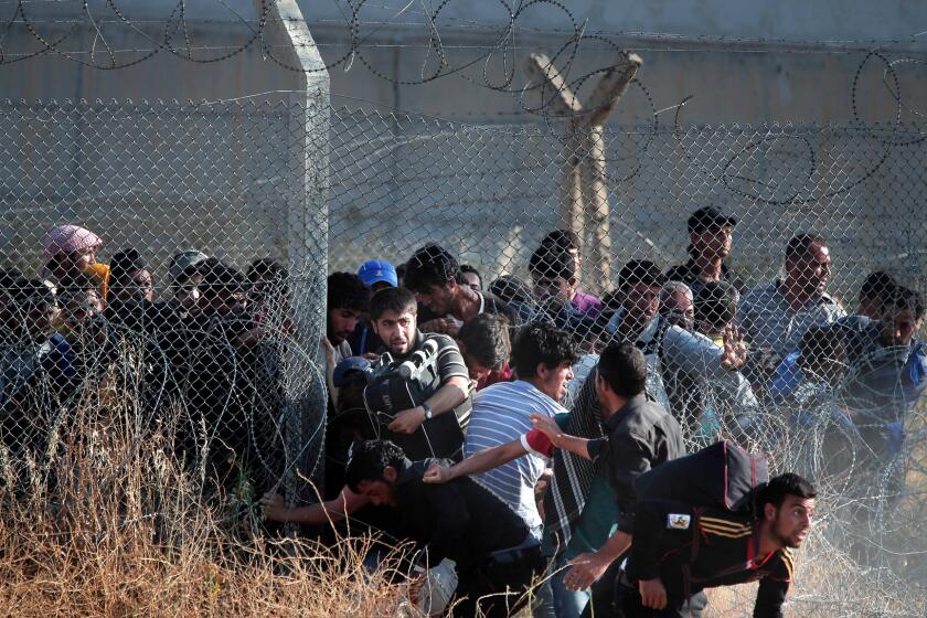 Syrian refugees burst into Turkey after breaking through a border fence and crossing the boundary separating the two countries in this June 14, 2015 photo. Turkey has been building a concrete wall along parts of the border in recent years.