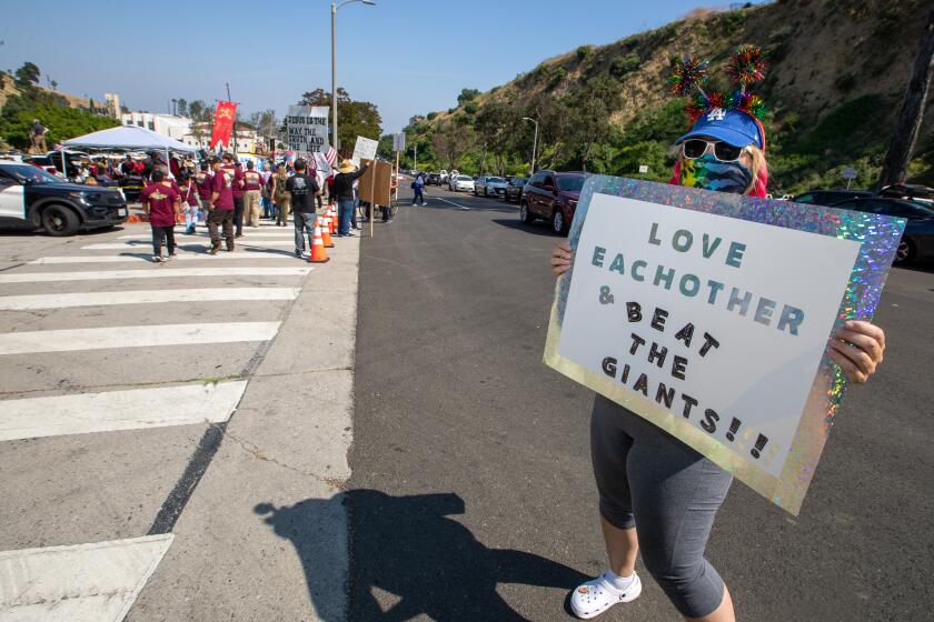 Jody Bender holds a sign for passing traffic near a gathering of Christian groups protesting near Dodger Stadium 