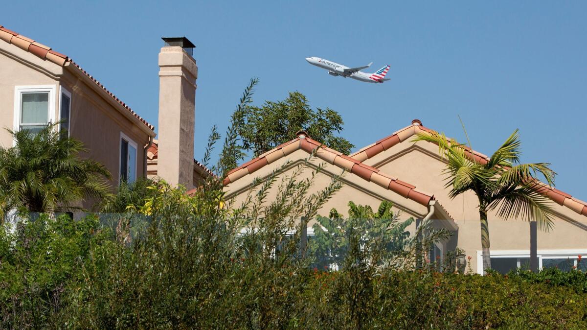 An American Airlines plane flies over homes along Upper Newport Bay in Newport Beach after taking off from John Wayne Airport on Tuesday.