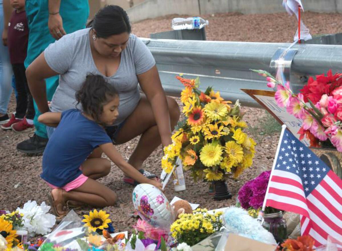 A family places flowers at a memorial outside the Cielo Vista Mall Walmart in El Paso, where 20 people were shot and killed by a gunman on Saturday. The El Paso massacre was followed on Sunday morning by a gunman’s killing of nine people in Dayton, Ohio. 