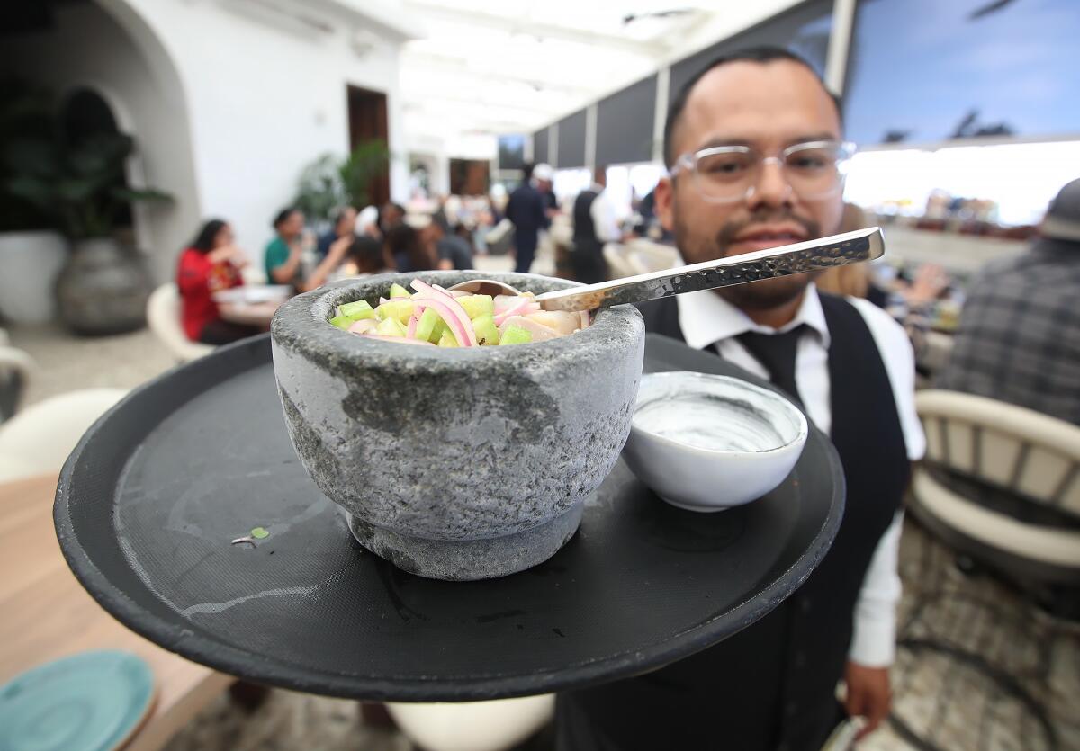 Server Francisco Del Carmen shows one of the ceviche bowls at the remodeled Javier's in Newport Coast in Newport Beach.