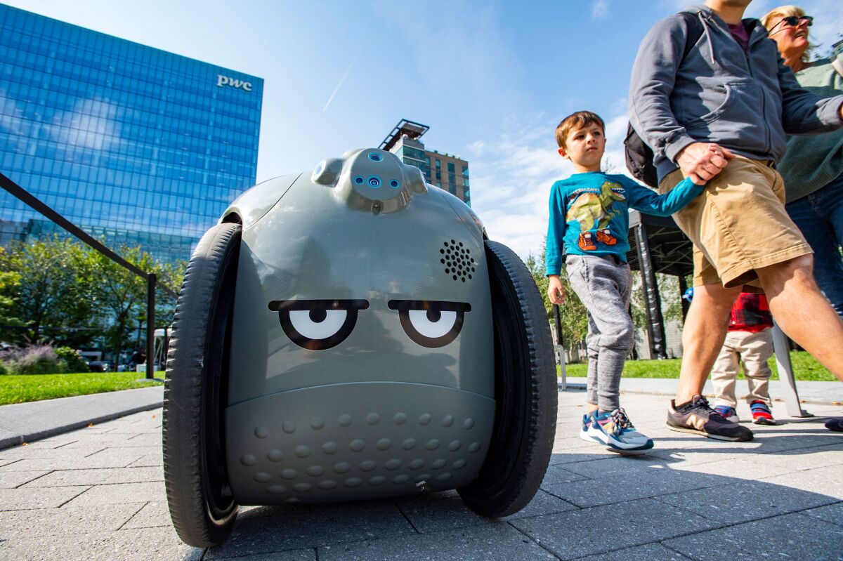 People walk by Gita, a robot by Piaggio