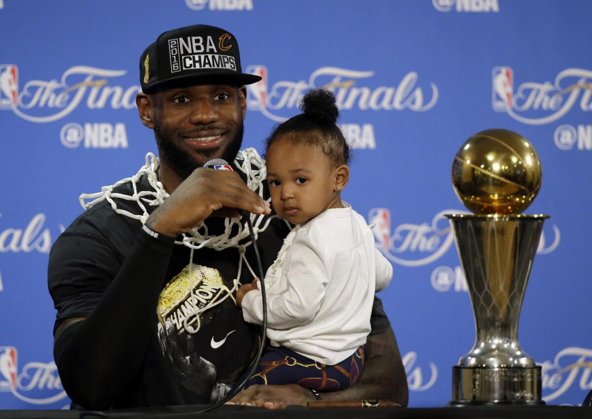 LeBron James answers questions as he holds his daughter Zhuri during a news conference after Game 7.