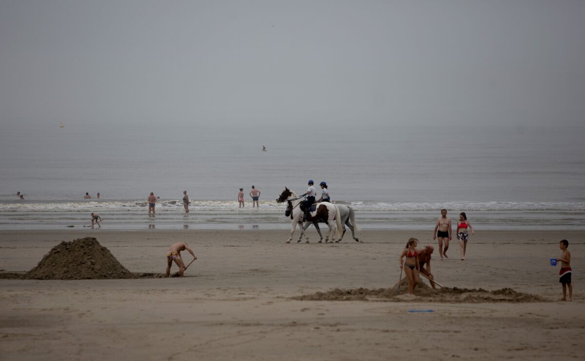 Police patrol the beach on horseback at the Belgian seaside resort of Blankenberge, Belgium, Tuesday, Aug. 11, 2020. A skirmish took place on the beach on Saturday, Aug. 8, 2020 which resulted in two coastal communities banning day trippers from the city. (AP Photo/Virginia Mayo)