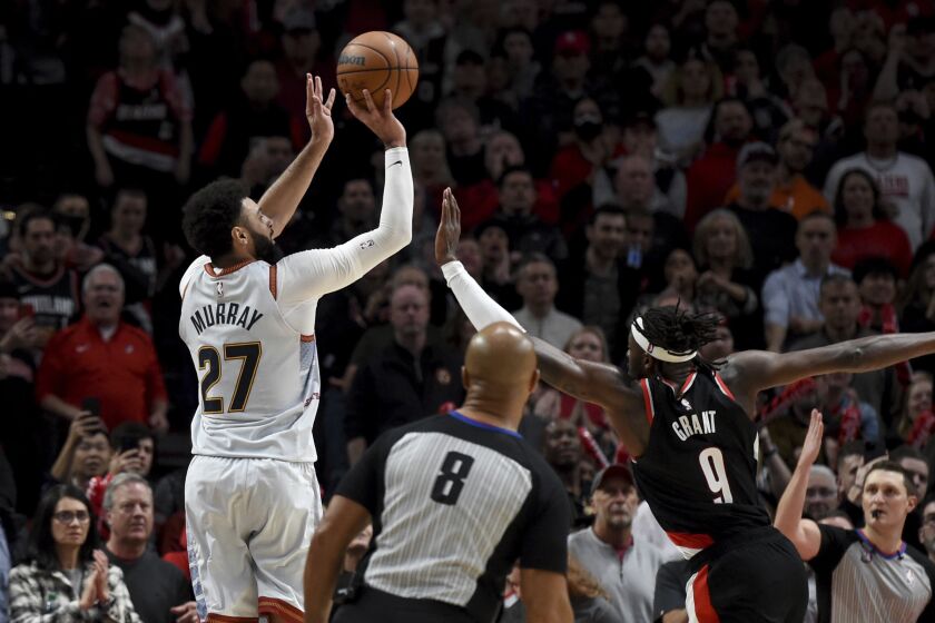Denver Nuggets guard Jamal Murray, left, hits a 3-pointer with less than a second left in the NBA basketball game as Portland Trail Blazers forward Jerami Grant, right, defends in Portland, Ore., Thursday, Dec. 8, 2022. The Nuggets won 121-120. (AP Photo/Steve Dykes)