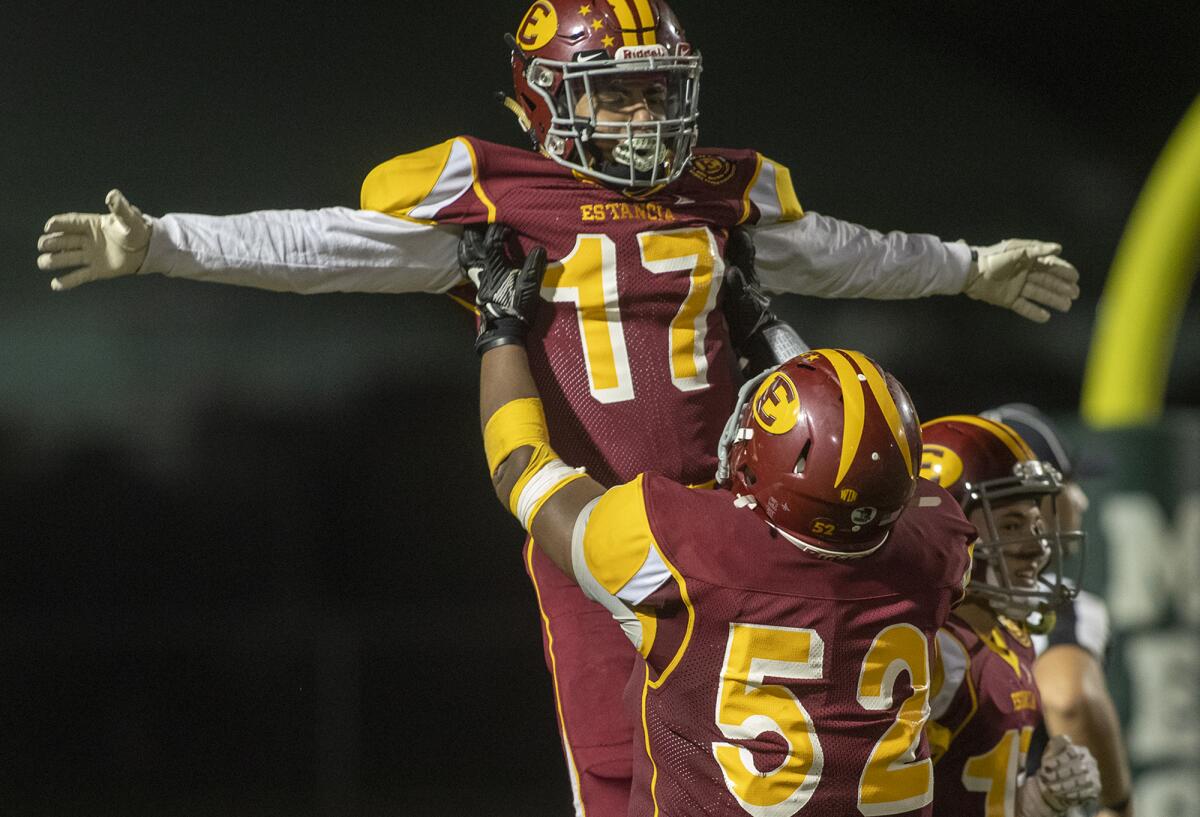 Estancia's Margarito Olivera lifts Beto Sotomayor after Sotomayor scored one of his two first-half touchdowns against Saddleback in an Orange Coast League game at Costa Mesa High on Thursday.