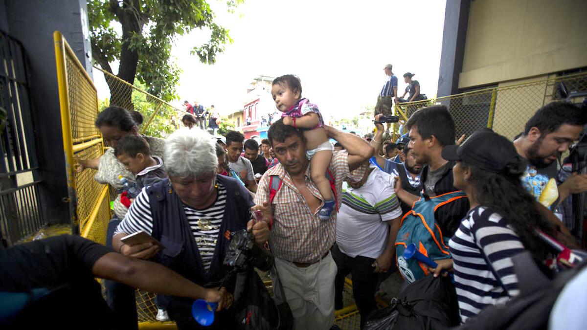 Migrantes hondureños se apresuran a cruzar la frontera con México tras derribar una valla en Tecun Uman, Guatemala.
