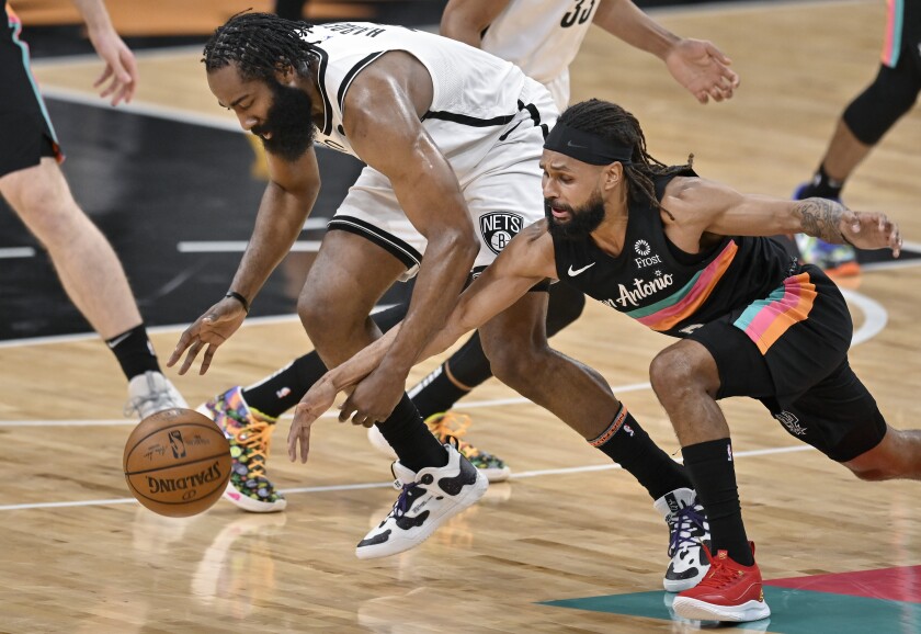 Brooklyn Nets' James Harden, left, and San Antonio Spurs' Patty Mills chase the ball during the first half of an NBA basketball game, Monday, March 1, 2021, in San Antonio. (AP Photo/Darren Abate)