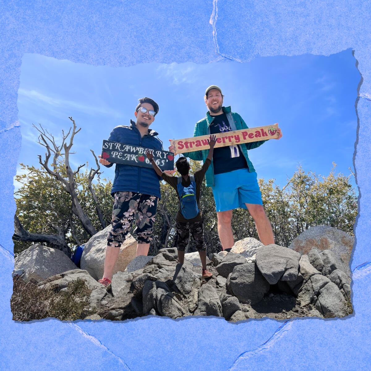 Two young men hold signs that say "Strawberry Peak."