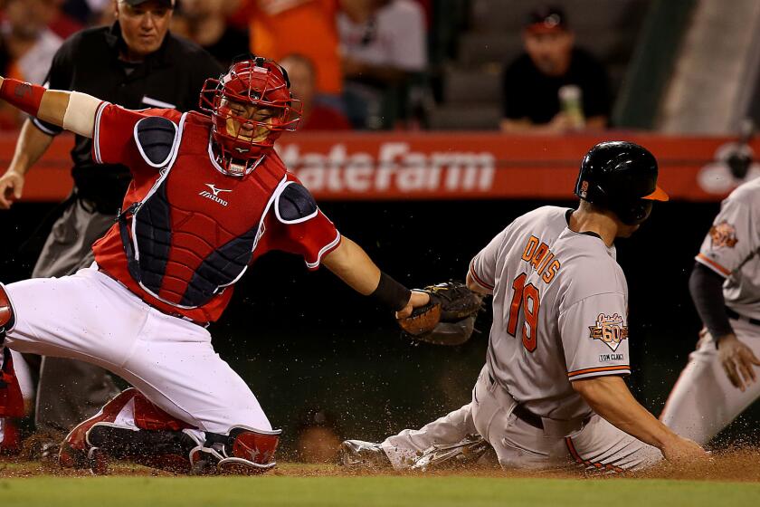 Baltimore's Chris Davis scores past Angels catcher Hank Conger on a double by teammate J.J. Hardy (not pictured) during the sixth inning of the Angels' 4-2 loss Tuesday.