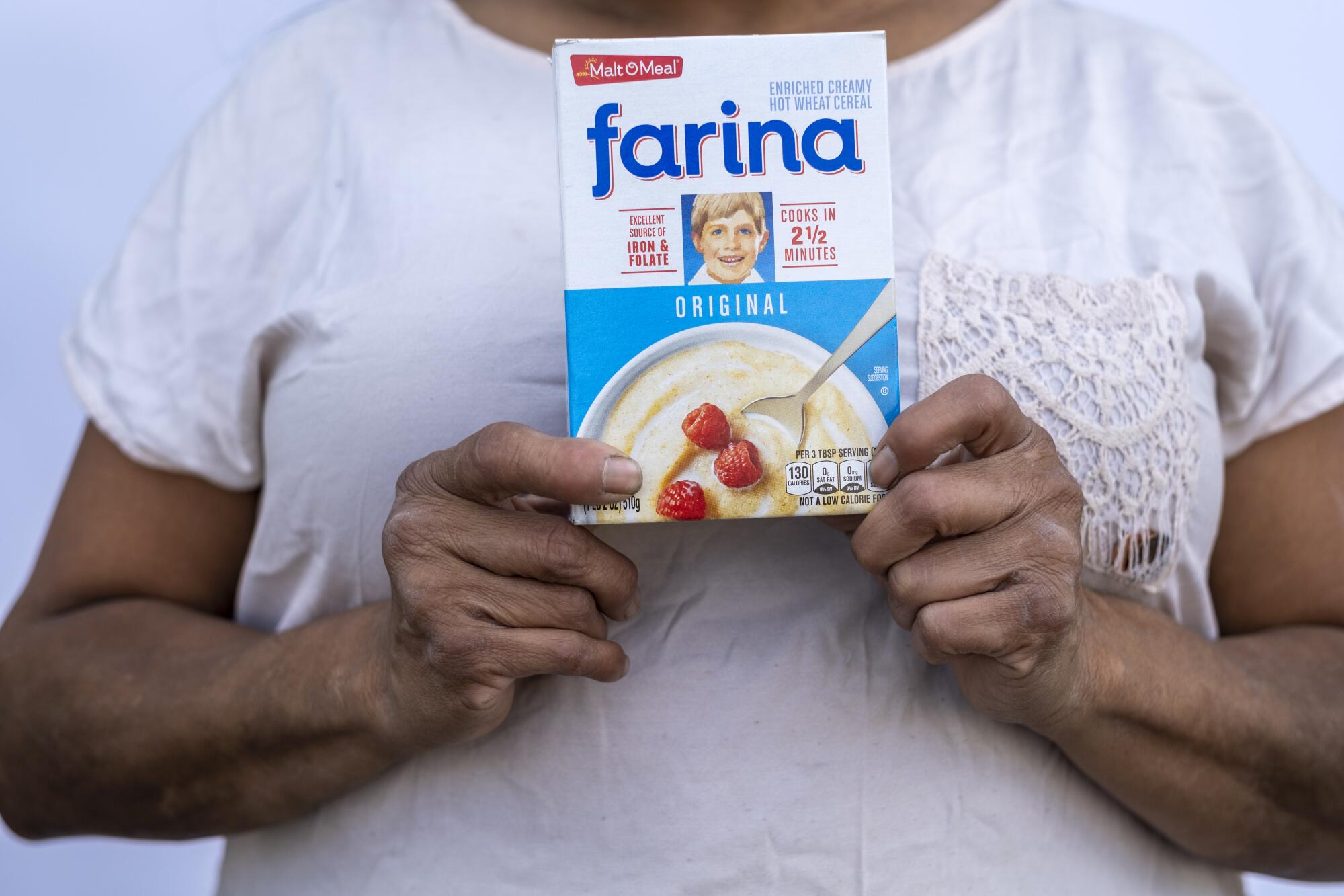 A woman holds a box of wheat cereal. 