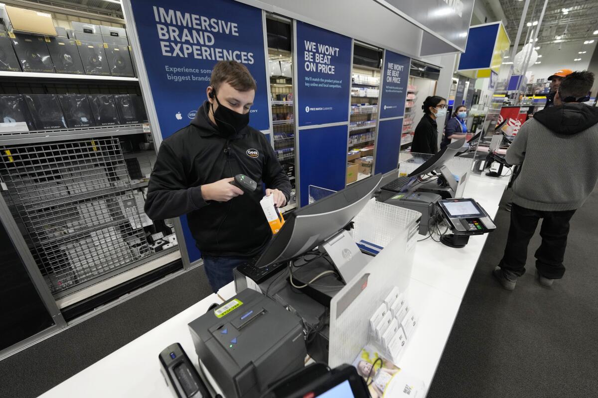 A sales associate processes the purchase of a hard drive at a Best Buy store.