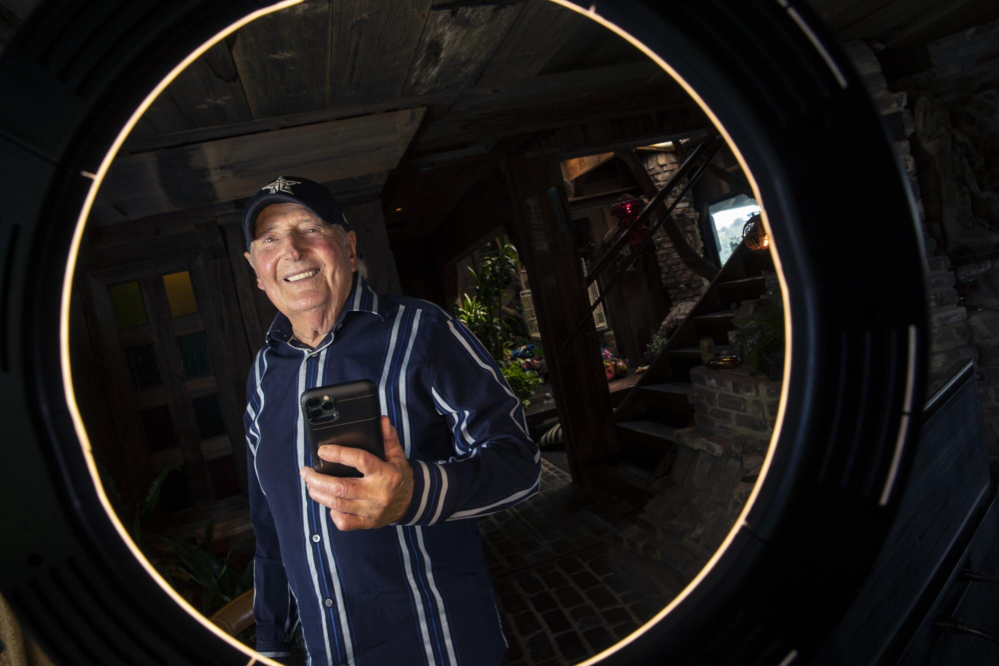Sid Krofft holds a phone as he's photographed at his home in Los Angeles.