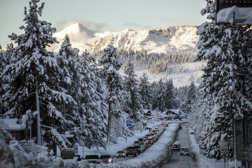 Vehicles travel along a snow-lined U.S. Route 50 the morning after a winter storm pelted the region with a large amount of snow, in South Lake Tahoe, Calif., Sunday, Jan. 1, 2023. (Stephen Lam/San Francisco Chronicle via AP)