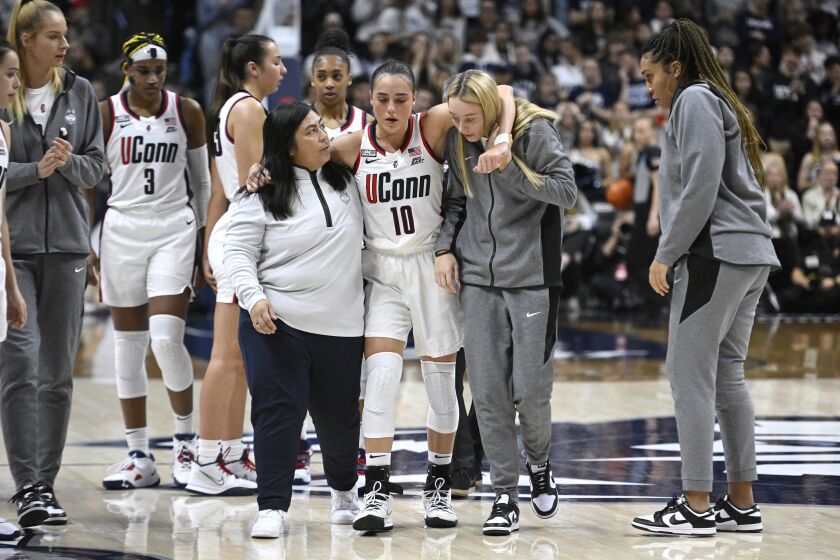 UConn's Nika Muhl (10) is helped off the court by athletic trainer Janelle Francisco, left, and teammate Paige Bueckers, right, during the second half of an NCAA college basketball game against Princeton, Thursday, Dec. 8, 2022, in Storrs, Conn. (AP Photo/Jessica Hill)